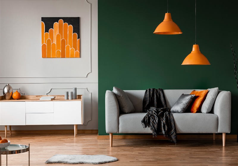 Imagem de uma sala de estar com uma parede verde e ornamentos na cor laranja