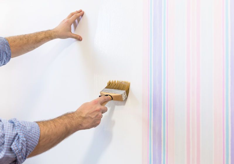 Imagem de pessoa aplicando papel de parede em ambiente interno