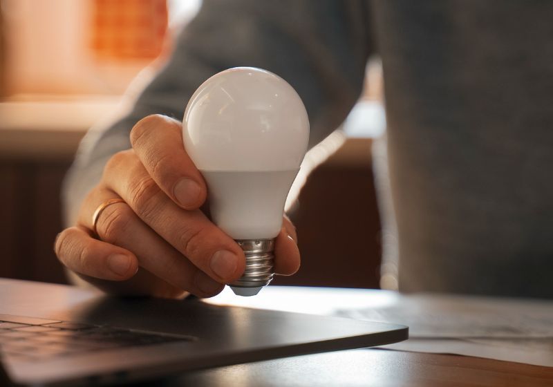 Pessoa segurando uma lâmpada LED moderna.